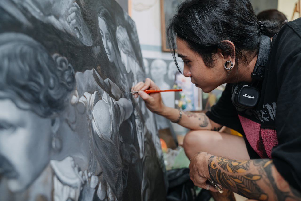 A focused artist skillfully details a black and white painting, showcasing intricate techniques.
